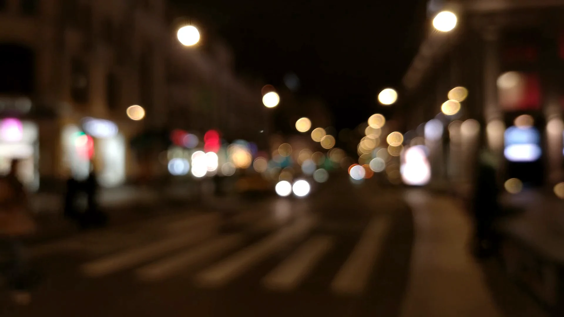 Luces de la ciudad de noche sobre el asfalto mojado, desenfocadas